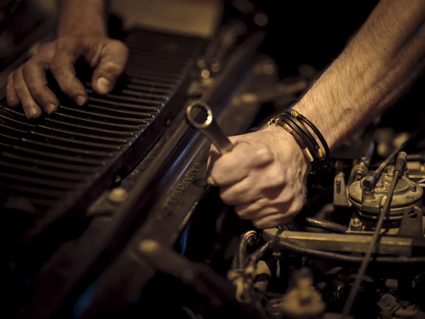 A mechanic's hands working a wrench on a car engine