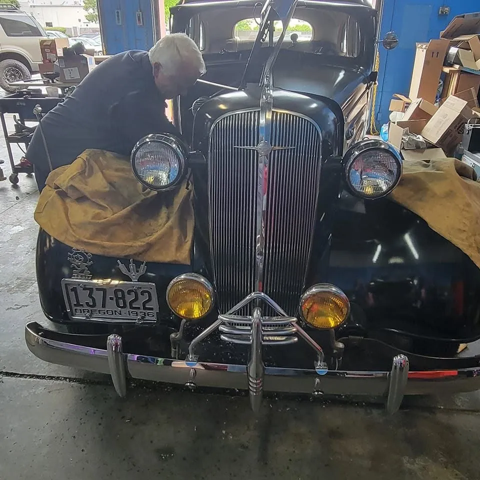 Russ leaning into the engine bay of a black 1936 Chevy in the RT Automotive shop